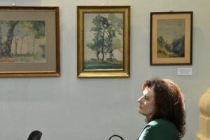 kobieta słuchająca koncertu, w tle ekspozycja - obrazy Zenona waśniewskiego