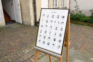 tablica z alfabetem hebrajskim ustawiona na sztaludze na dziedzińcu muzeum