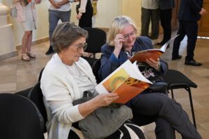 zwiedzający wystawę Żółte w zielonym przeglądają katalog towarzyszący wystawie