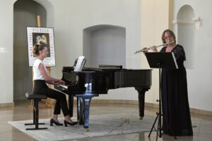 Dyrygentka chóru Cantate Deo gra na flecie poprzecznym przy akompaniamencie fortepianu