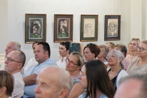 publiczność słuchająca występu, w tle litografie Picassa na ścianie